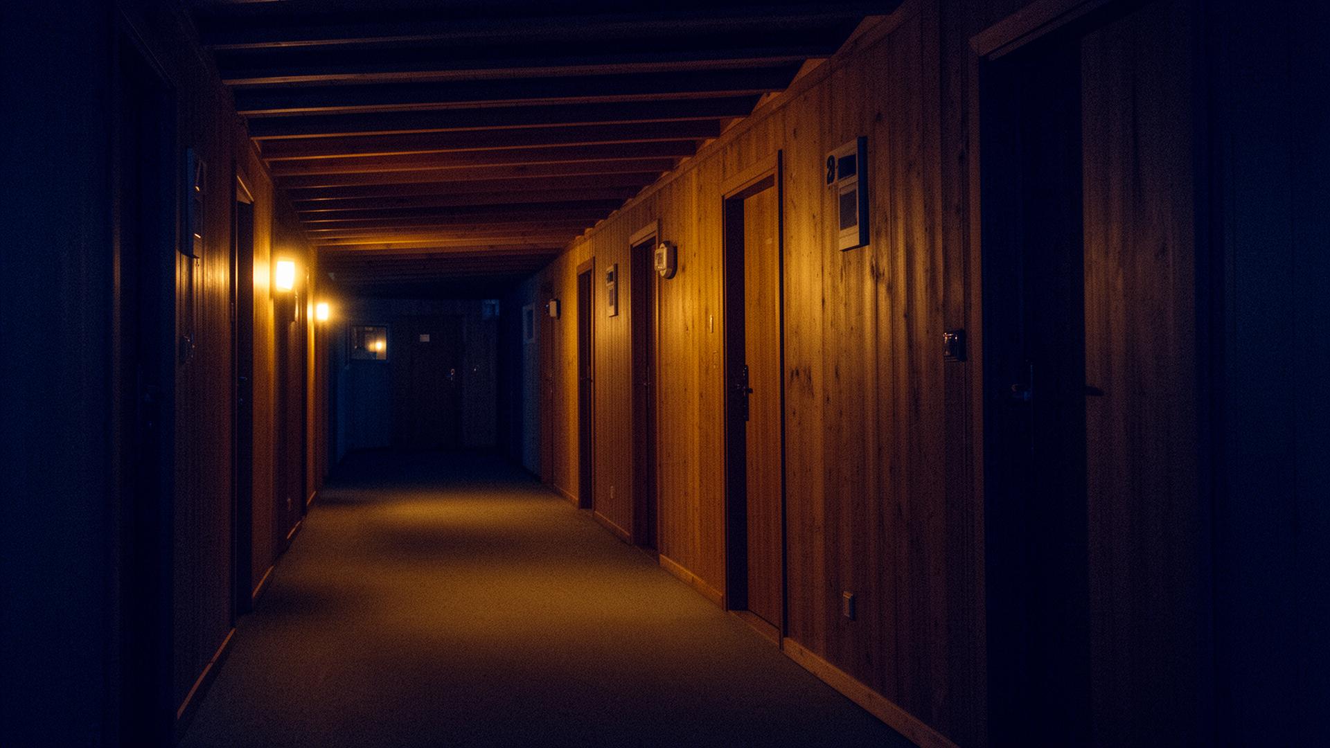 Pasillo de un albergue iluminado tenuemente por luces cálidas durante la noche